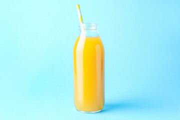 Tasty mango juice in glass bottle on light blue background