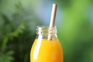 Tasty mango juice in glass bottle on blurred background, closeup