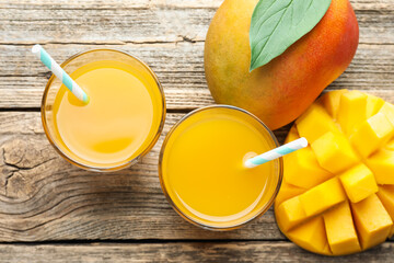 Tasty mango juice in glasses and fresh fruits on wooden table, flat lay