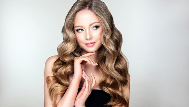 Fototapeta Blonde  girl with long  and   shiny wavy  hair .  Beautiful  model woman with curly hairstyle . Beauty and cosmetology