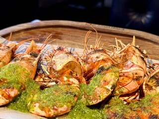 Dish of fried lobsters and shrimps with a side dish of fresh herbs, on a wooden board, ideal for...