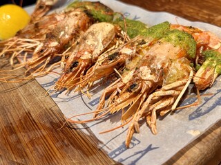 Dish of fried lobsters and shrimps with a side dish of fresh herbs, on a wooden board, ideal for any feast. A vibrant grilled seafood dish elegantly garnished with fresh herbs for a delicious look
