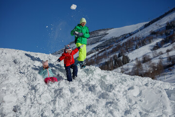 Three sibling have fun snow fighting on mountain slope after ski