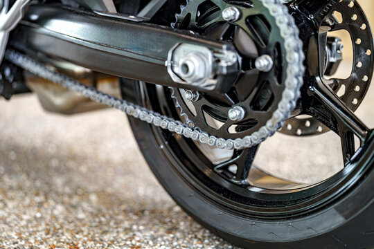 Close-up view of motorcycle chain and wheel details during maintenance at a garage
