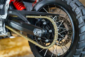 Close-up of a detailed motorcycle rear wheel with chain and gears captured indoors showcasing...