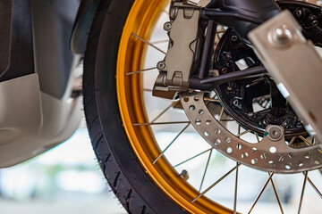Motorcycle wheel with golden rim and brake system captured in bright garage setting during...