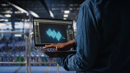 Close up of admin in data center using laptop to monitor neural network LLM visualization. Server...