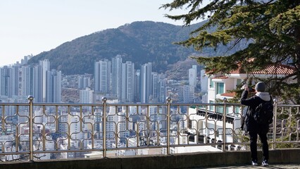 Man looking out towards a dense cityscape with mountains in the background