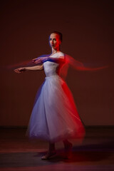 Fototapeta premium Caucasian woman dancing classical dance in tutu . Long exposure photo. 