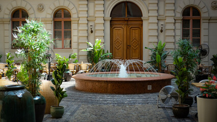 Cozy courtyard with central fountain, lush greenery, and classic European architecture.