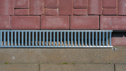 Top view of modern drainage grate and textured pavement in urban infrastructure design.