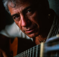 Elderly guitarist and singer songwriter captured in a moody dimly lit setting soulful expression and timeless musical presence.