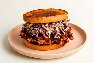 Vegan BBQ jackfruit sandwich with slaw on pastel peach plate