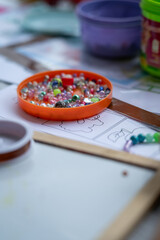 Orange lid containing threading beads for children's creativity. 
