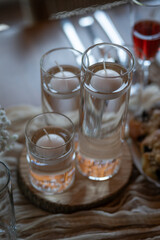 Three glasses of water with floating, unlit candles on the surface.
