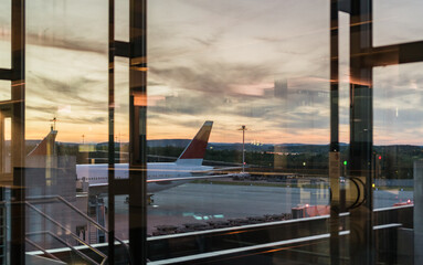 Airplane parked at the gate, seen through a window from inside the airport terminal. Travel and transportation concept.