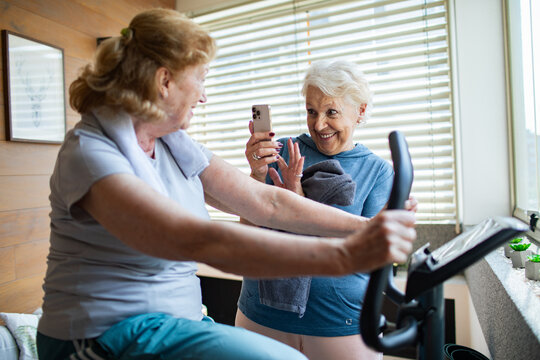 Senior lesbian couple exercising together at home and cheering each other on - Powered by Adobe
