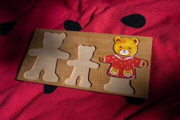 An old wooden children's mold for assembling bear figurine parts, lying on a red blanket. 

