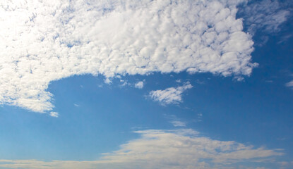 Expansive blue sky with fluffy white clouds creating a serene atmosphere, showcasing the beauty of...