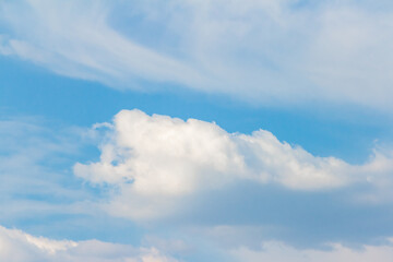 Soft white clouds drift across a bright blue sky, creating a serene atmosphere with gentle textures...