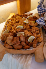 Two types of small fried schnitzels on a large wooden tray at a buffet-style table. 
