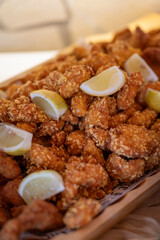 Two types of small fried schnitzels on a large wooden tray at a buffet-style table. 

