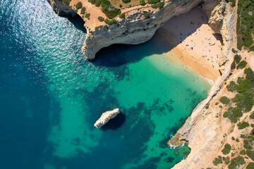 Beachgoers sunbathe while surrounded by limestone cliffs in the Algarve, Portugal
