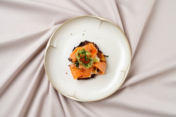Succulent pieces of cured salmon rest on a crispy base, garnished with vibrant herbs. The plate's simplicity highlights the gourmet presentation in an upscale environment