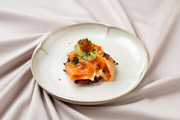 An exquisite dish showcasing slices of smoked salmon artfully arranged atop creamy avocado with a sprinkle of vibrant herbs