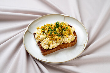 A delicious open-faced sandwich showcases creamy egg salad adorned with fresh herbs, resting on...