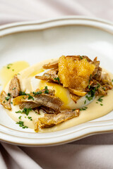 A poached egg nestled on velvety sauce, topped with golden, crispy garnishes and a drizzle of rich oil. Fresh herbs add color, presenting a refined culinary creation that captivates the palate