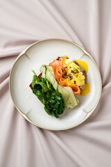 A beautifully arranged plate features vibrant salmon, fresh cucumber, and sautéed spinach, creating a perfect balance of flavors and colors. Ideal for a gourmet brunch experience