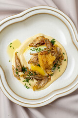 A plate presents a creative dish with golden crispy vegetables artfully arranged atop a velvety sauce, enhanced with fresh herbs. Light and elegant, it invites the palate