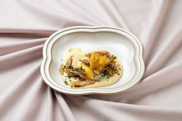A beautifully arranged dish presents a rich and creamy puree topped with crispy garnishes, expertly crafted in a modern restaurant's elegant setting, highlighting seasonal ingredients