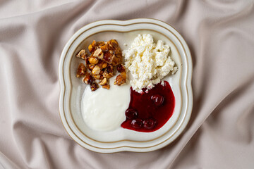 A beautifully arranged plate holds creamy yogurt, fresh cottage cheese, and vibrant cherry compote, showcasing a delightful mix of flavors and textures perfect for breakfast or brunch
