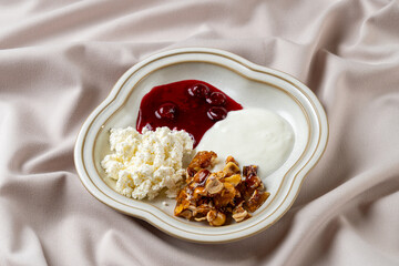 A beautifully arranged breakfast featuring rich cottage cheese, smooth yogurt, and a sweet berry compote, all presented on a decorative plate against a soft backdrop