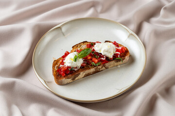 A beautifully arranged bruschetta features toasted bread topped with vibrant diced tomatoes, fresh basil, and rich dollops of creamy burrata
