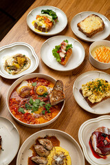 Colorful plates filled with various gourmet brunch items are artfully arranged on a rustic wooden table, showcasing culinary creativity and vibrant flavors in a welcoming café atmosphere