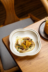 Delight in a beautifully plated dish featuring crispy fish atop a creamy base, garnished with herbs and a drizzle of olive oil, all set against warm wooden textures