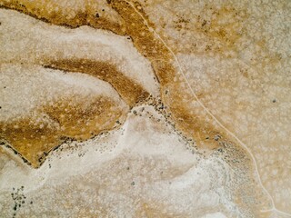 Aerial view of a dry, arid landscape in  Carrizo Plain National Monument, California, USA. The image shows a network of dirt roads and trails winding through the sparse vegetation.