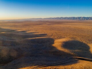 Aerial view of Carrizo Plain National Monument, California, USA. The photo shows the vast, open landscape with rolling hills, dry grasslands, and distant mountains.