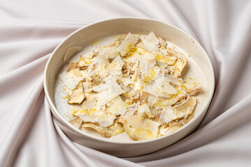 A delectable creation featuring thin slices of chicken on a creamy base, enhanced by shavings of cheese and a drizzle of high-quality olive oil, evoking a sense of gourmet delight