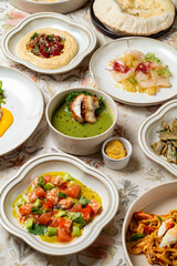 A vibrant assortment of Mediterranean cuisine is displayed on a floral tablecloth, showcasing fresh ingredients. Guests savor delicious flavors in a warm and inviting ambiance at dinner