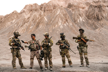 Special Forces Team Standing Together in Desert Mountain Terrain – Tactical Soldiers in Full Gear...