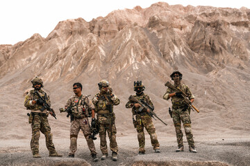 Special Forces Team Standing Together in Desert Mountain Terrain – Tactical Soldiers in Full Gear...