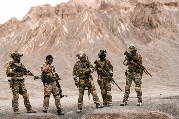 Special Forces Team Standing Together in Desert Mountain Terrain – Tactical Soldiers in Full Gear...
