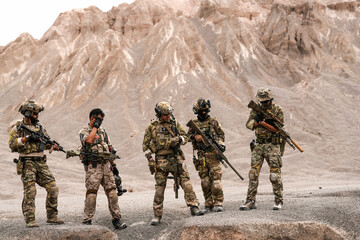 Special Forces Team Standing Together in Desert Mountain Terrain – Tactical Soldiers in Full Gear...