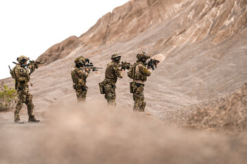 Special Forces Team Standing Together in Desert Mountain Terrain – Tactical Soldiers in Full Gear...
