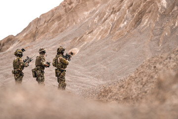 Special Forces Team Standing Together in Desert Mountain Terrain – Tactical Soldiers in Full Gear...