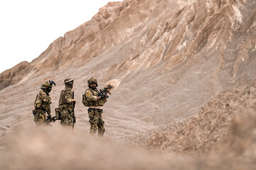 Special Forces Team Standing Together in Desert Mountain Terrain – Tactical Soldiers in Full Gear...